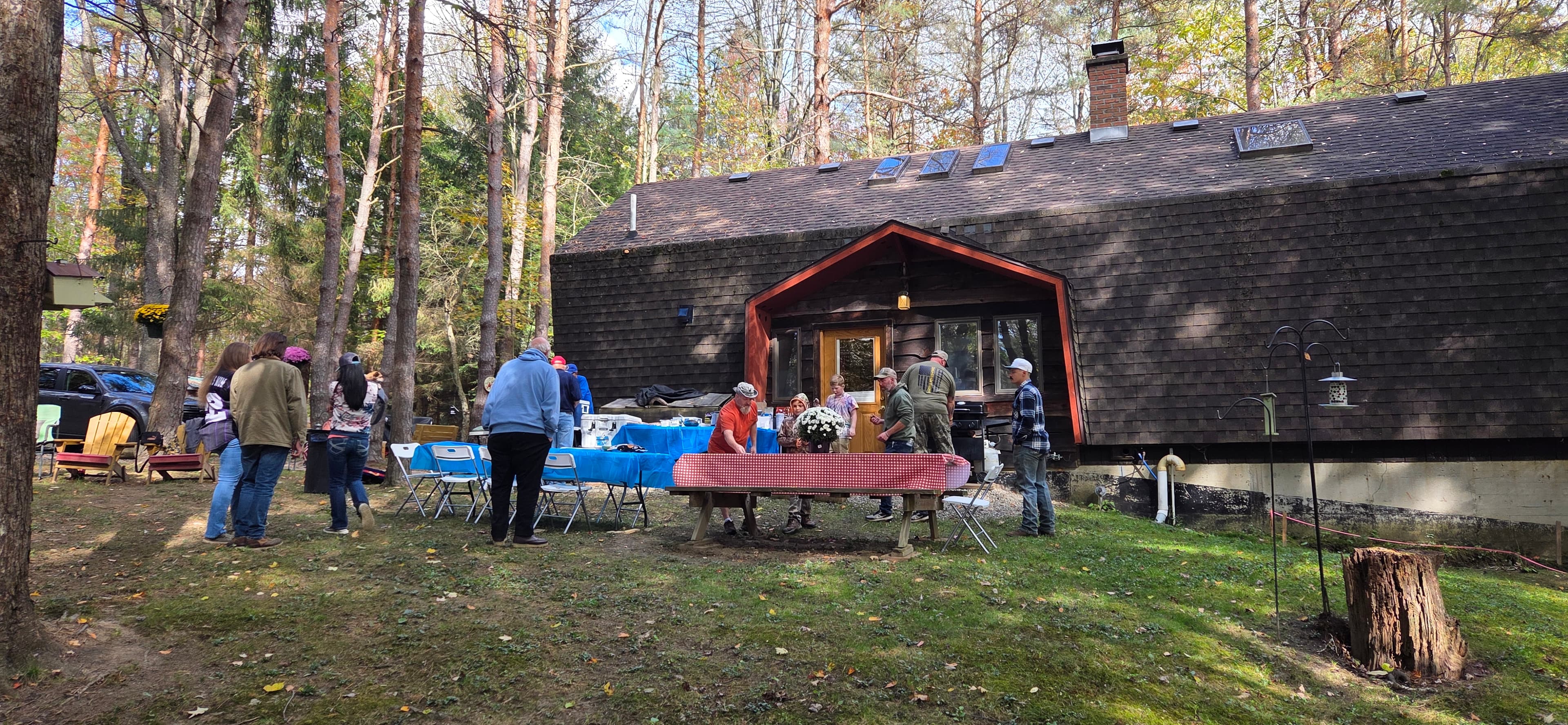Neighbors setting up tables and chairs outside the cabin before a fall gathering