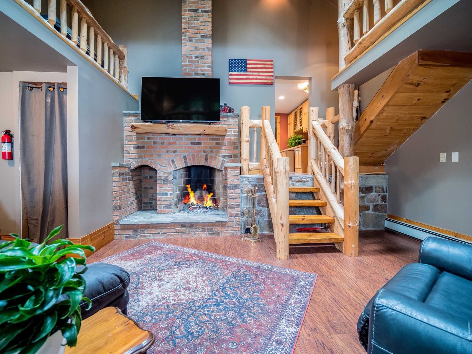 The lodge living room with a stone fireplace, log railings, and an American flag on the wall